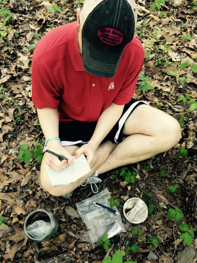 man sitting on the ground and writing 