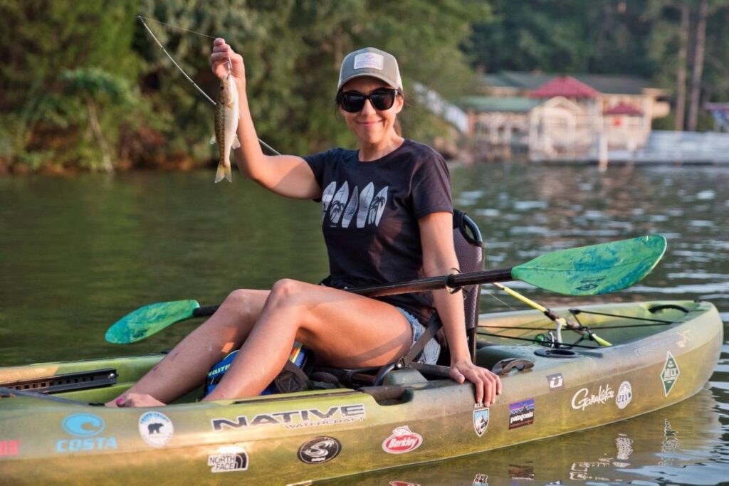 girl in kayak holding fish 