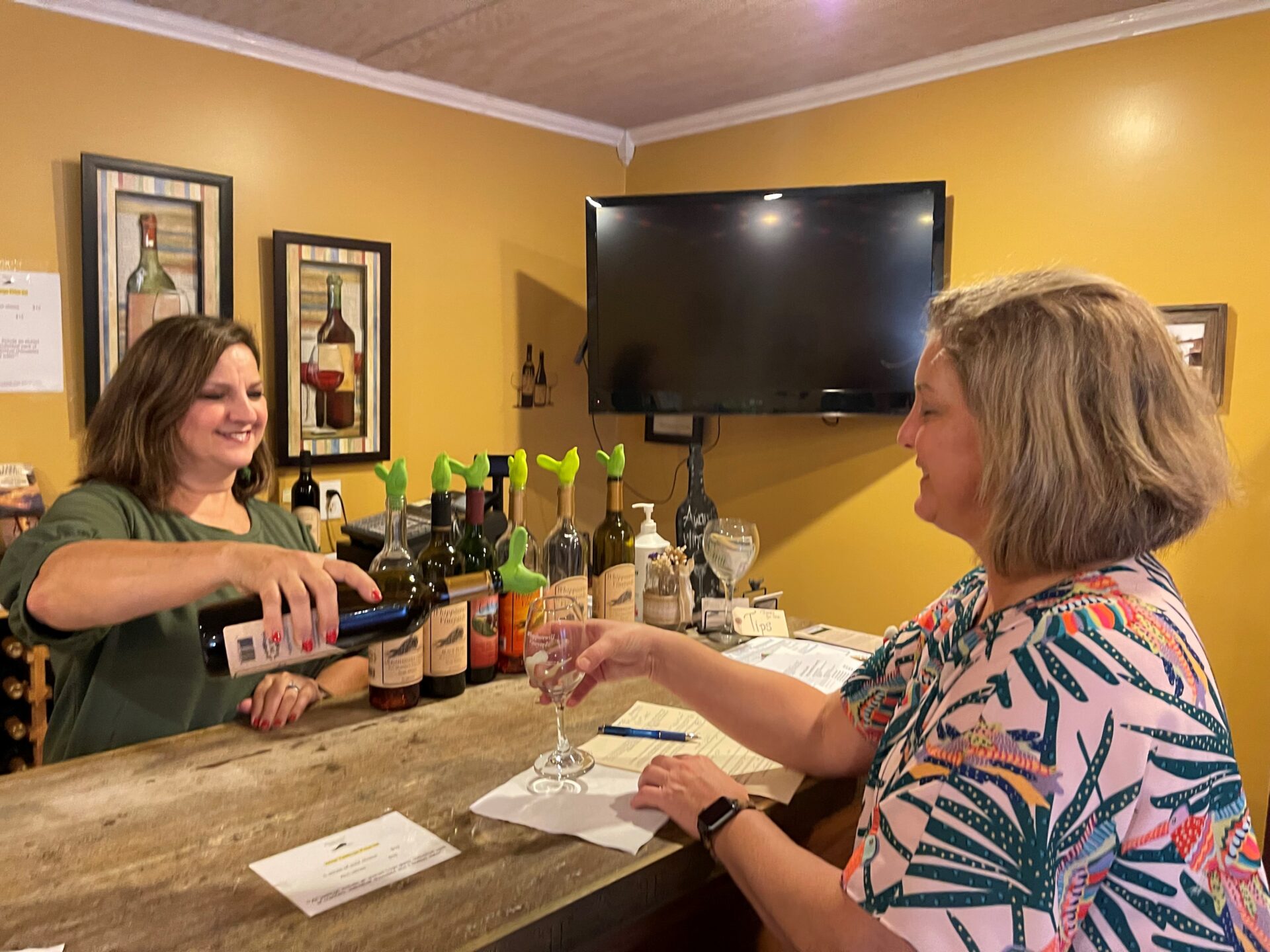 woman pouring wine into another woman's glass