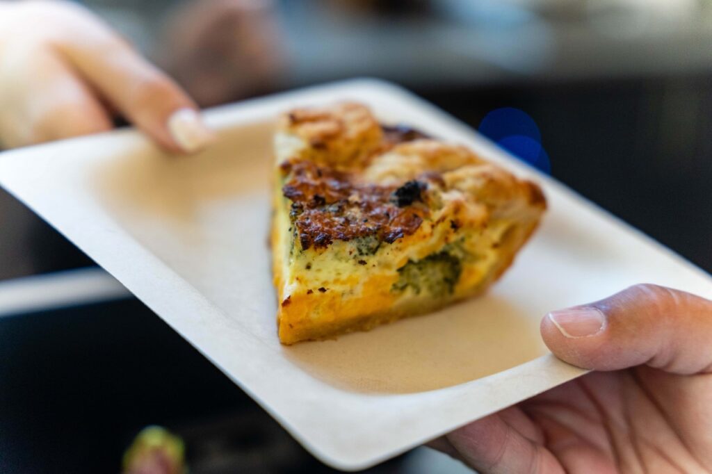 A person holds out a plate with quiche on it