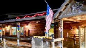 Exterior of Red Hill Gallery at night, a log cabin-style building with a flag hanging out front