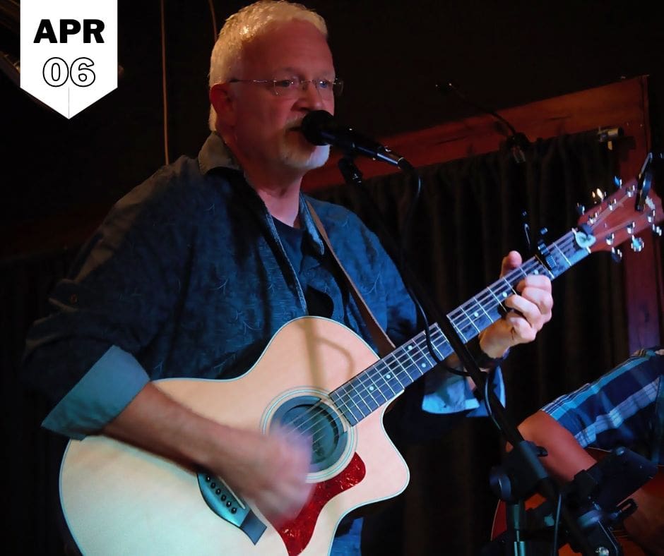 A man singing in front of the mike and playing guitar