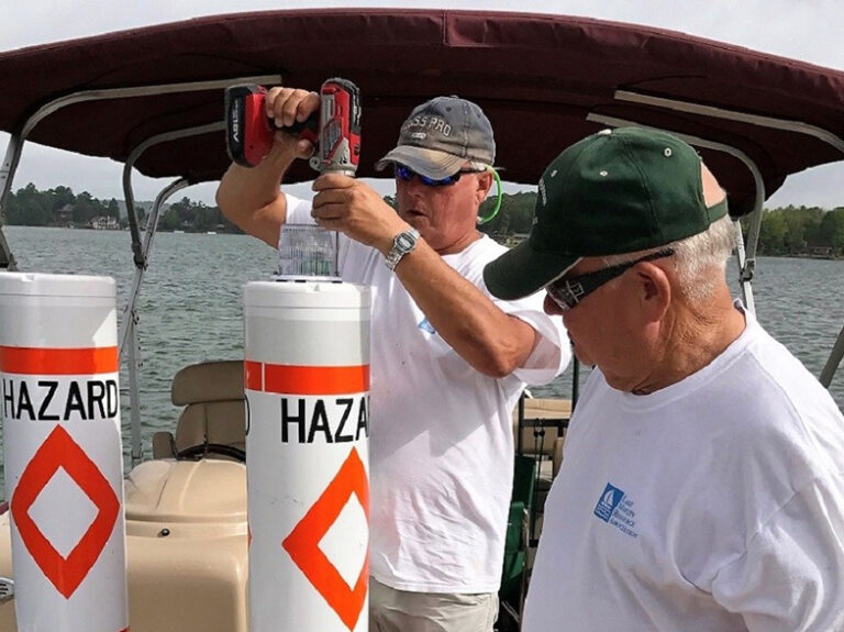 One man drills into a hazard buoy while another looks on