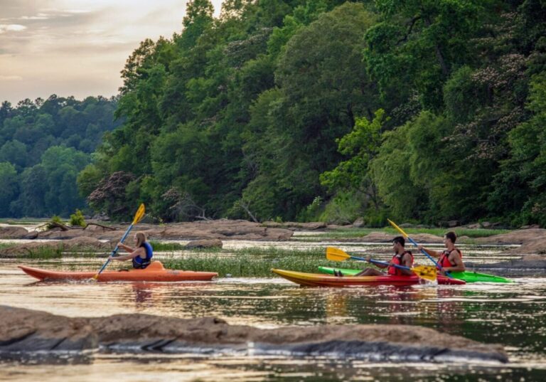 Kayakers on a river with green hills behind