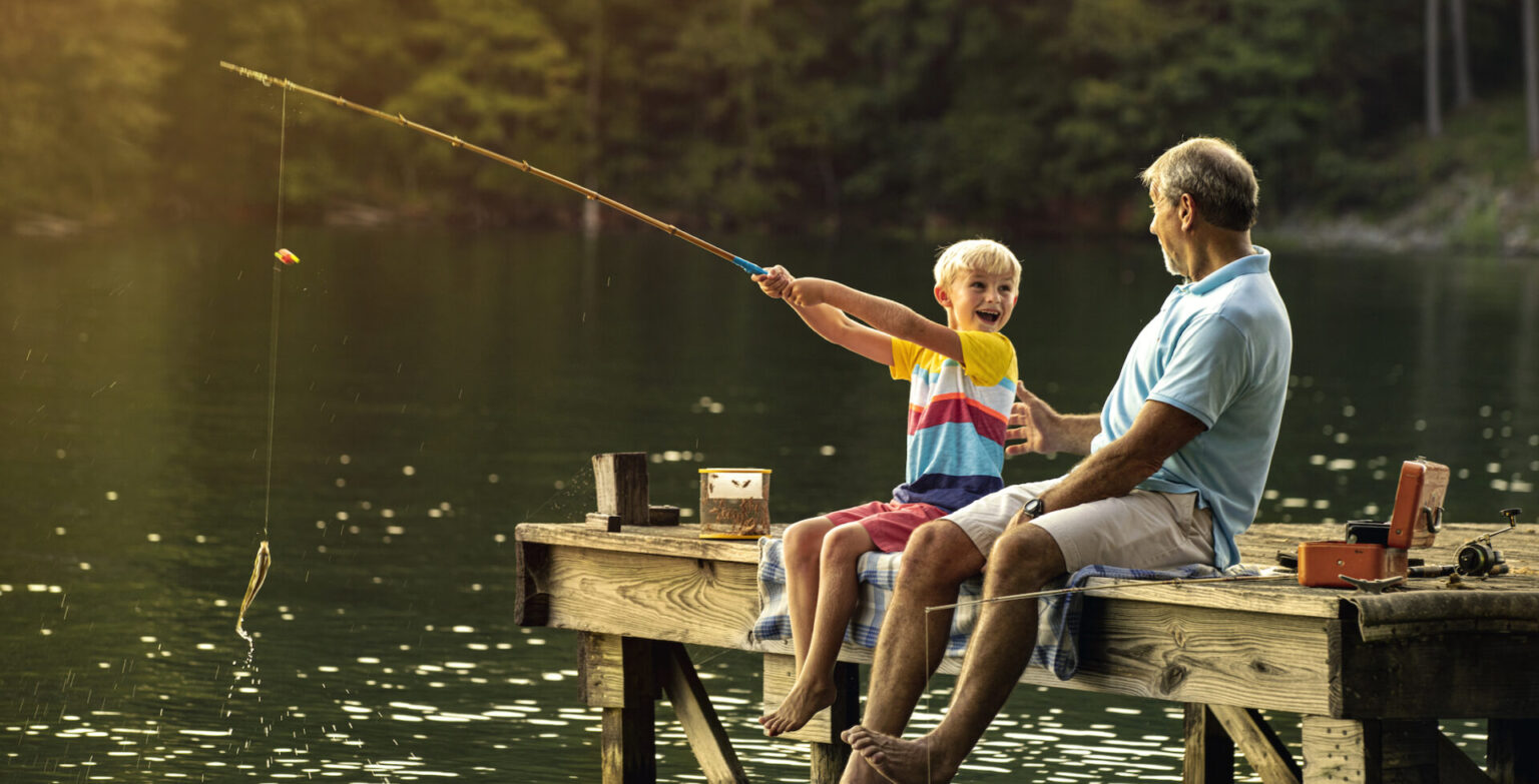 An smiling older man and a child fish from a dock