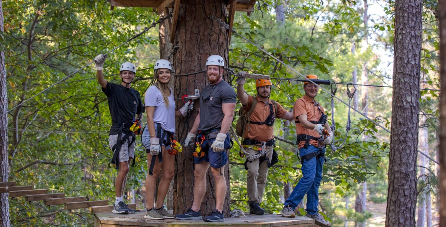 A group of people stand on a zipline platform