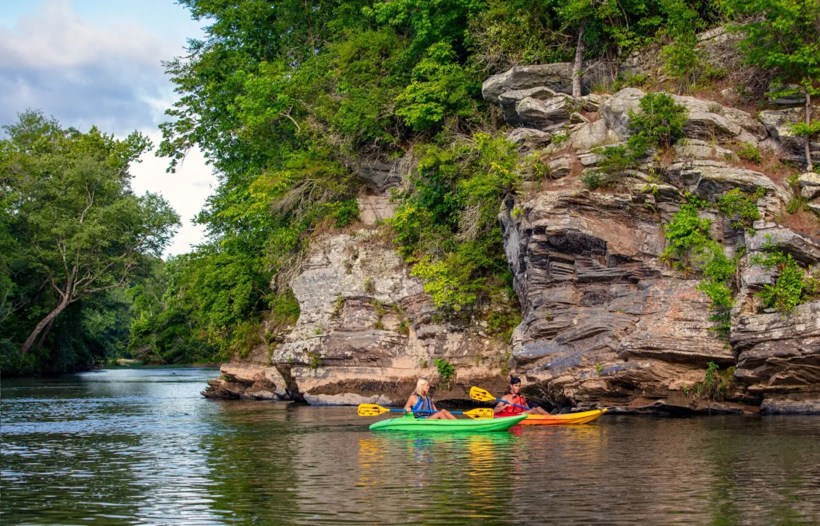 Two kayakers float past a rocky outcropping