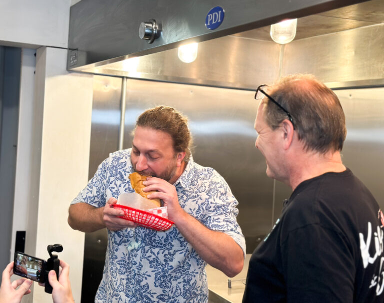 A man takes a bite out of a po boy sandwich