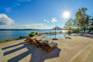 Patio chairs and a lakeside pool on a sunny day