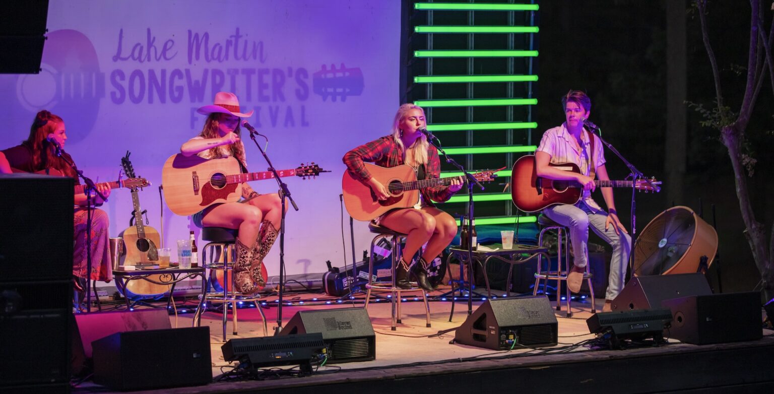 A trio of musicians performs on a neon-lit stage