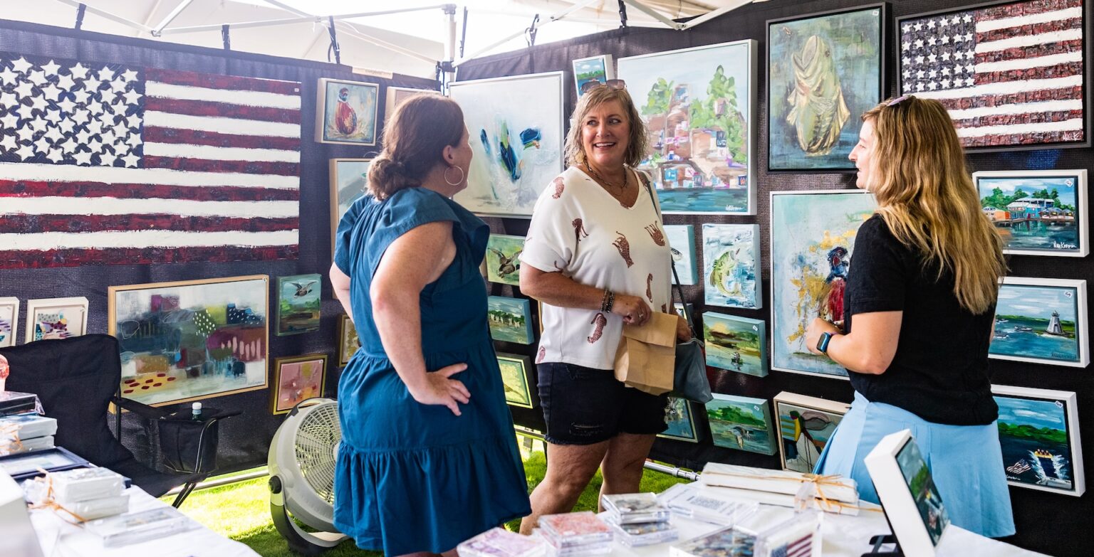 Two women chat at an outdoor arts market