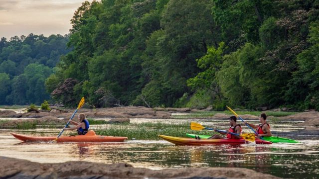 Kayakers on a river with green hills behind